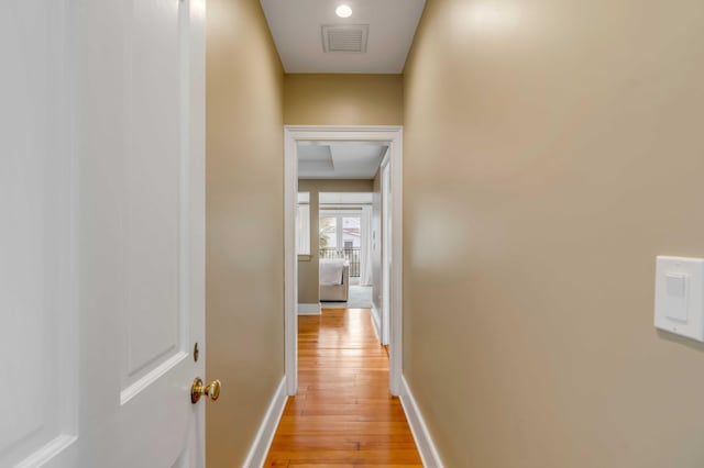 corridor featuring light wood-type flooring, baseboards, and visible vents