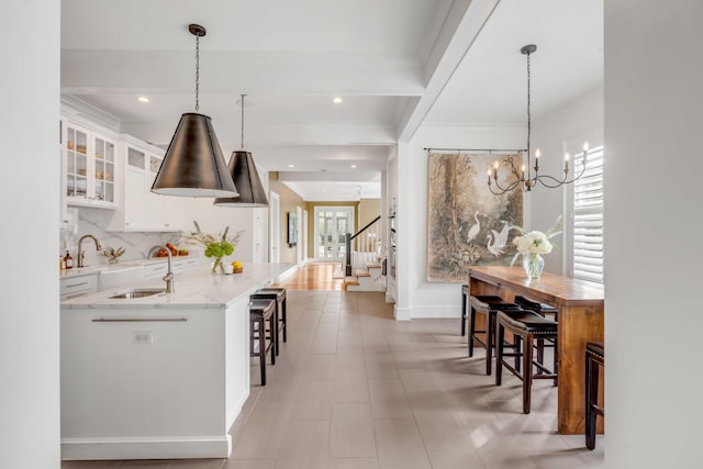 interior space with light stone counters, a breakfast bar, backsplash, glass insert cabinets, and white cabinets