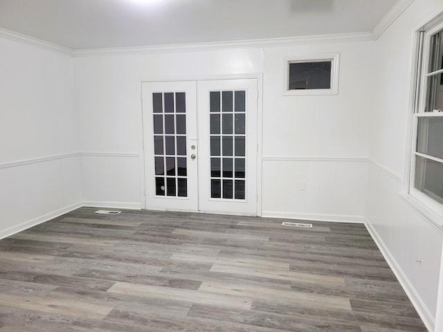 empty room featuring hardwood / wood-style floors, crown molding, and french doors