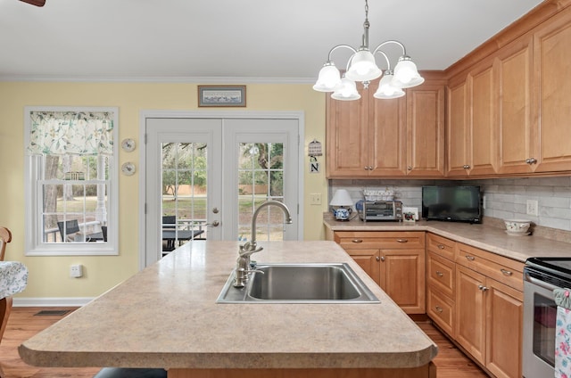 kitchen with sink, a kitchen island with sink, tasteful backsplash, and pendant lighting