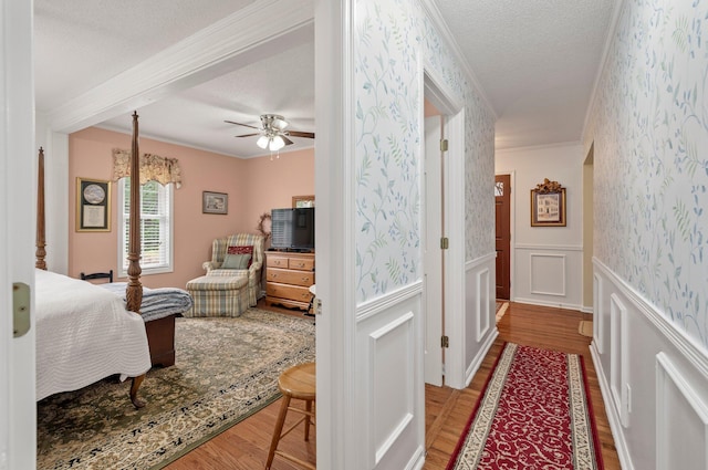 bedroom featuring a textured ceiling, hardwood / wood-style floors, crown molding, and ceiling fan