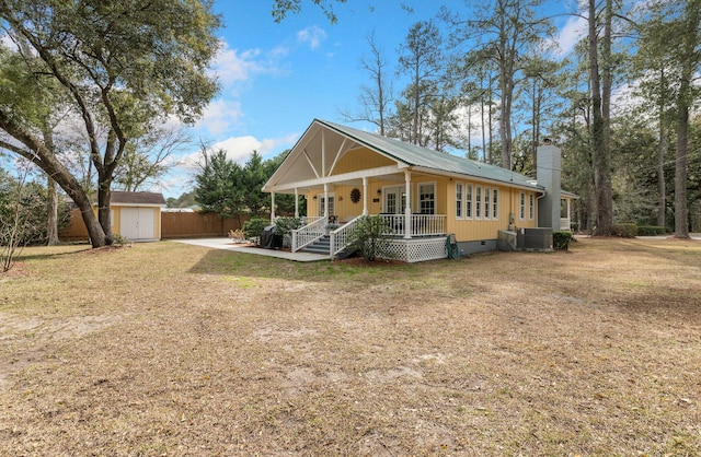 view of front facade with a shed, central AC, a front yard, and covered porch