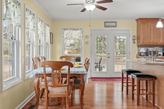 dining space featuring light wood-type flooring, plenty of natural light, sink, and ornamental molding