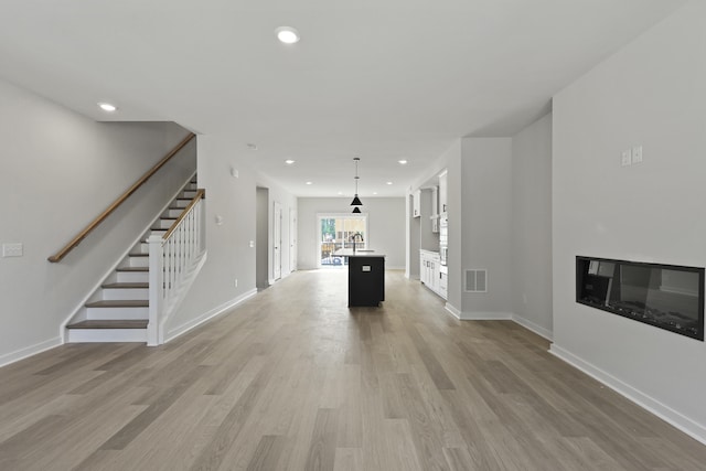 564 Scholar Way, Summerville, SC 29486 - unfurnished living room featuring stairs, light wood finished floors, recessed lighting, and a glass covered fireplace