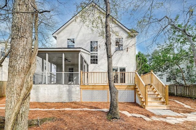 rear view of house featuring stairway, fence, a deck, and a sunroom