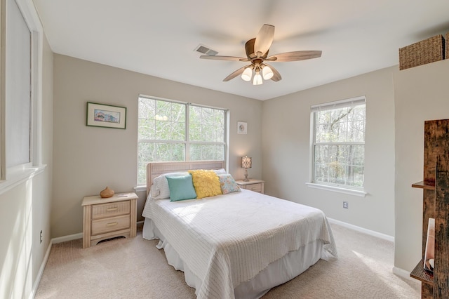 bedroom featuring visible vents, light colored carpet, baseboards, and multiple windows