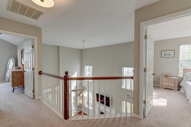 hall with visible vents, baseboards, and carpet floors