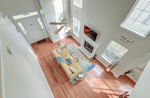 living area featuring wood finished floors, baseboards, a towering ceiling, and a fireplace with raised hearth