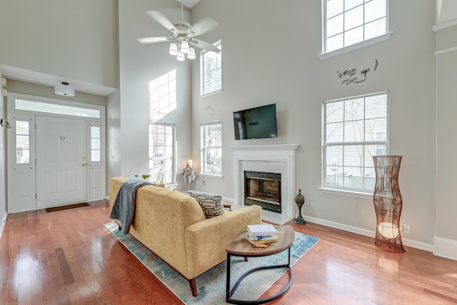 living room with baseboards, a ceiling fan, wood finished floors, and a fireplace