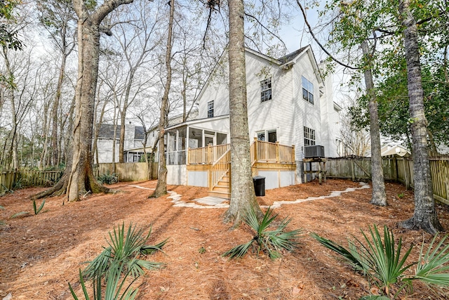 rear view of house featuring a deck, stairs, a fenced backyard, and a sunroom