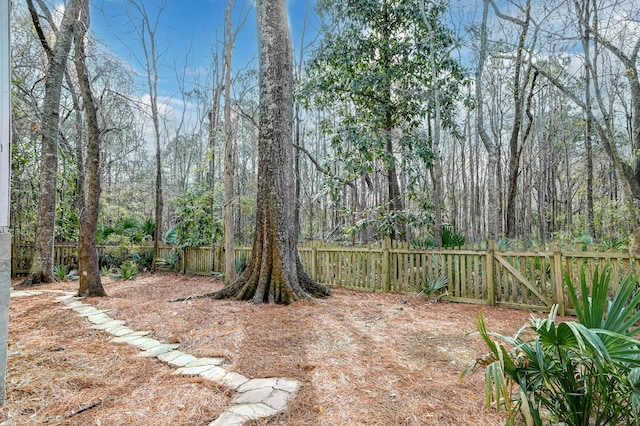 view of yard featuring a wooded view and fence