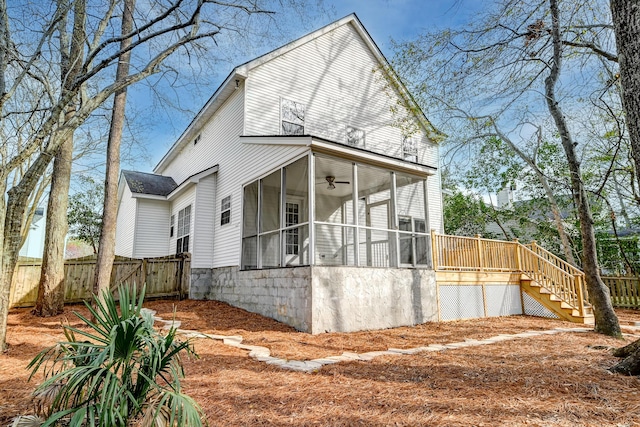 view of property exterior with a ceiling fan, fence, stairs, and a sunroom