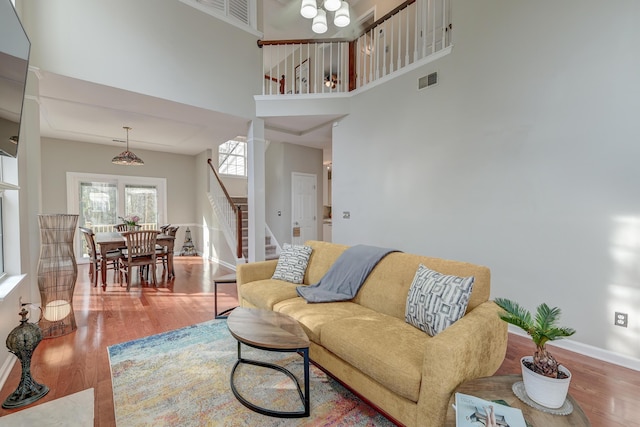 living room featuring visible vents, wood finished floors, stairway, a high ceiling, and baseboards