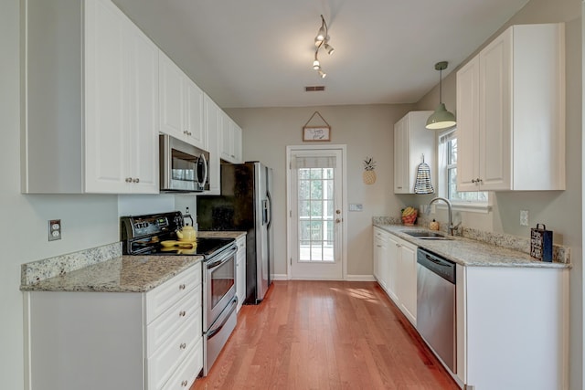 kitchen featuring visible vents, a sink, white cabinetry, light wood-style floors, and appliances with stainless steel finishes