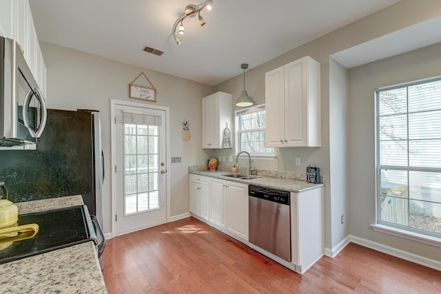 kitchen featuring visible vents, light wood-type flooring, stainless steel appliances, white cabinetry, and a sink