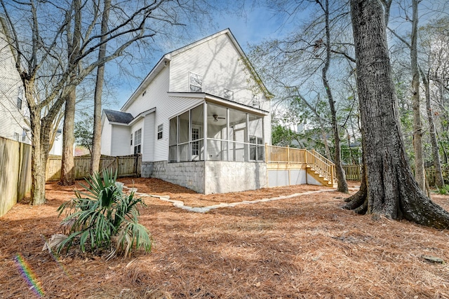 view of front of house with stairway, a ceiling fan, a fenced backyard, and a sunroom