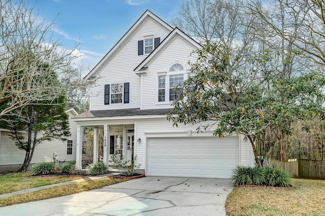 traditional-style home with covered porch, an attached garage, concrete driveway, and fence