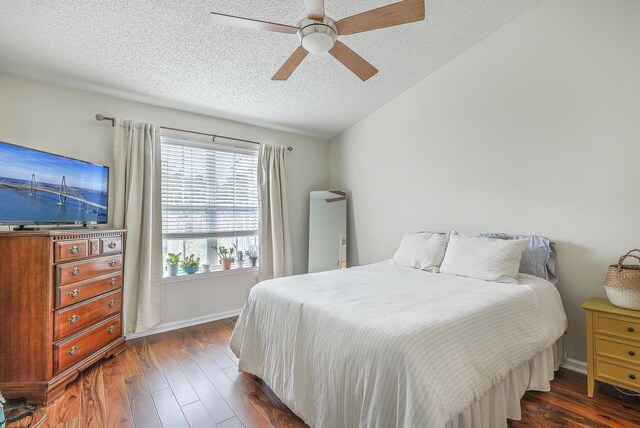 bedroom with ceiling fan, a textured ceiling, and dark wood-type flooring