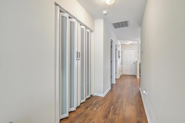 hall featuring a textured ceiling and dark wood-type flooring