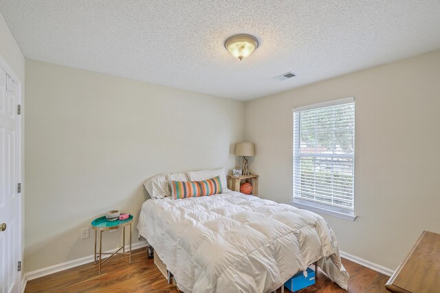 bedroom featuring a textured ceiling and dark hardwood / wood-style floors