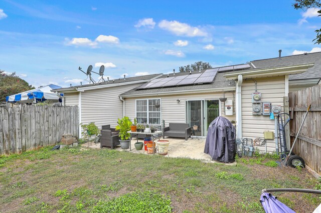 back of property with a lawn, solar panels, and a patio