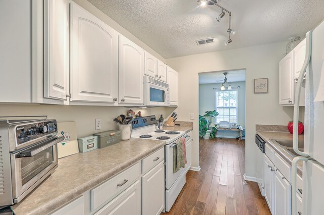 kitchen featuring a textured ceiling, track lighting, dark hardwood / wood-style floors, white cabinets, and white appliances