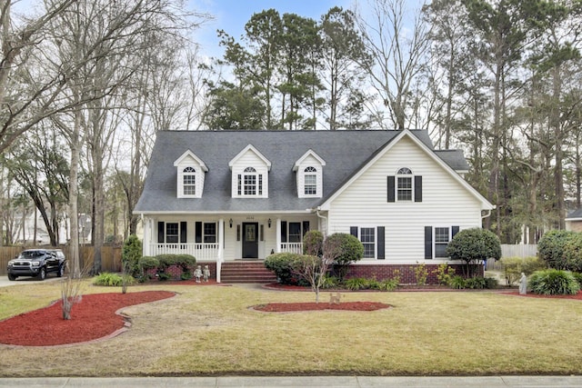 cape cod home with a porch, brick siding, fence, and a front lawn