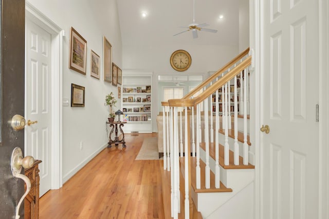 corridor with lofted ceiling, stairway, light wood-type flooring, and baseboards