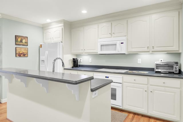 kitchen featuring white appliances, a toaster, a center island with sink, dark countertops, and white cabinetry