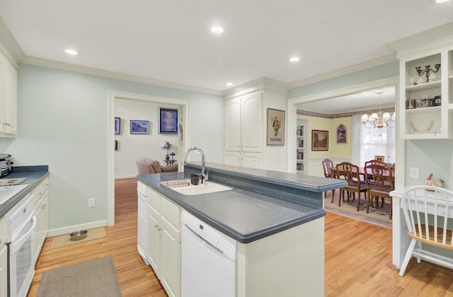 kitchen featuring dark countertops, white cabinetry, a sink, an island with sink, and white appliances