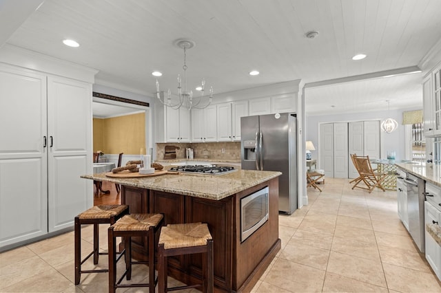 kitchen featuring pendant lighting, appliances with stainless steel finishes, a center island, and white cabinetry