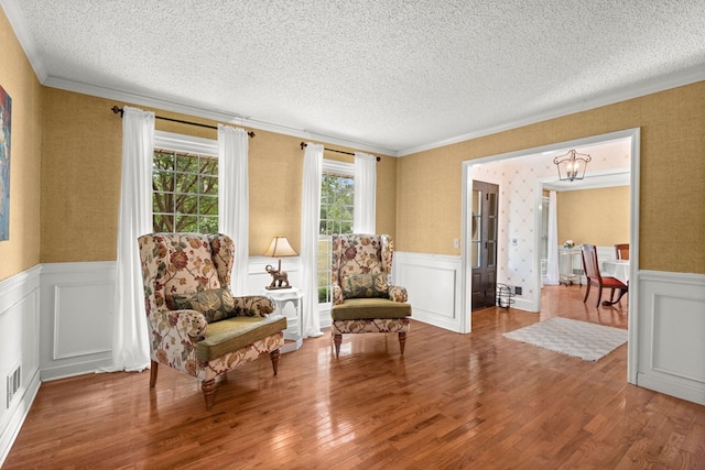 living area with a notable chandelier, ornamental molding, hardwood / wood-style flooring, and a textured ceiling