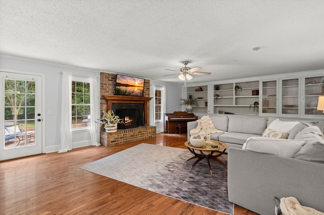 living room with a fireplace, wood-type flooring, a textured ceiling, and ceiling fan