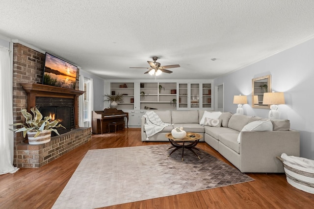 living room with a brick fireplace, wood-type flooring, and a textured ceiling