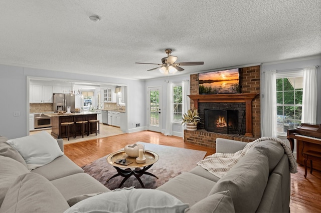 living room with light wood-type flooring, a wealth of natural light, and ceiling fan