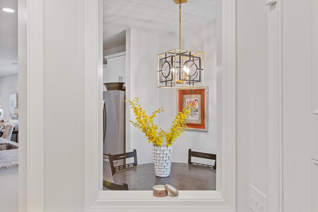interior details with freestanding refrigerator, a sink, and an inviting chandelier