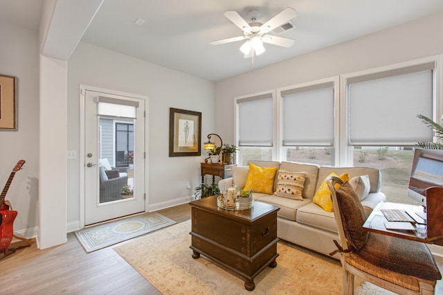 living room featuring light wood finished floors, visible vents, ceiling fan, and a healthy amount of sunlight