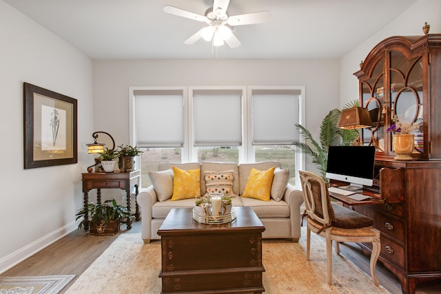 office space with baseboards, light wood-type flooring, and a ceiling fan