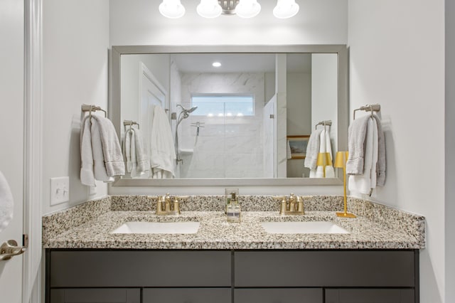 full bath featuring double vanity, tiled shower, and a sink