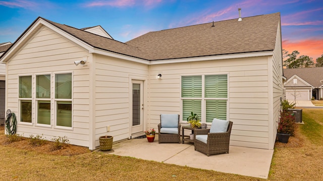 rear view of property with a shingled roof, a yard, and a patio area