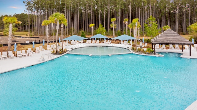 community pool with fence, a gazebo, and a patio area