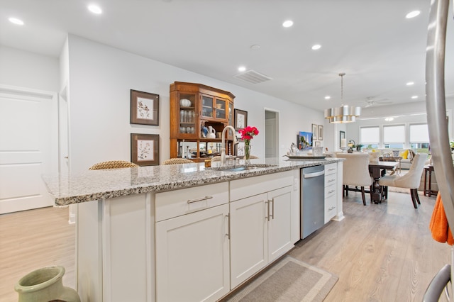 kitchen featuring a sink, open floor plan, white cabinets, light wood-style floors, and recessed lighting