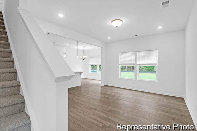 interior space with visible vents, stairway, wood finished floors, an inviting chandelier, and recessed lighting