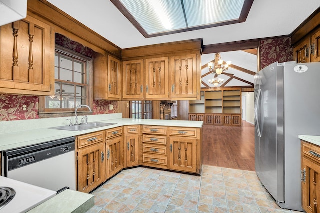 kitchen with sink, an inviting chandelier, stainless steel refrigerator, white dishwasher, and kitchen peninsula