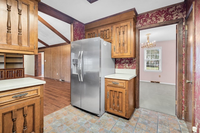 kitchen with an inviting chandelier, stainless steel fridge with ice dispenser, light tile patterned floors, and wood walls