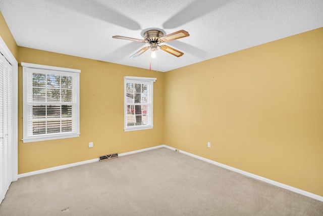 empty room featuring carpet flooring, a textured ceiling, and ceiling fan