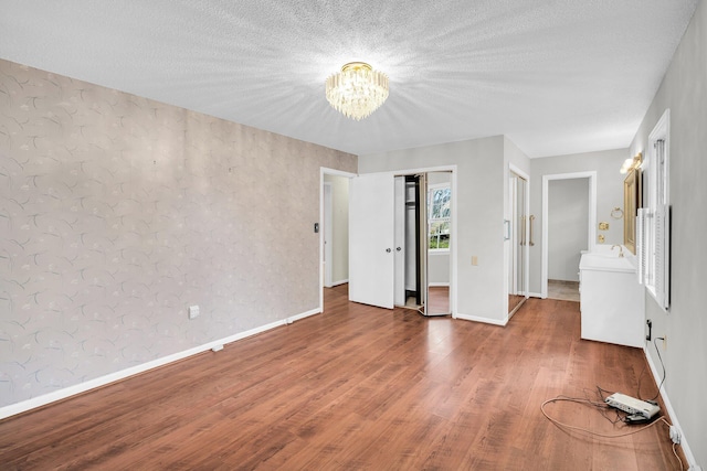 unfurnished bedroom with an inviting chandelier, sink, and hardwood / wood-style floors