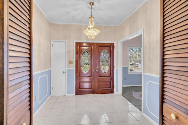 tiled foyer entrance featuring a notable chandelier and crown molding