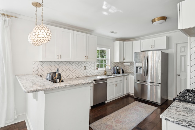 kitchen with white cabinets, dark wood finished floors, a sink, decorative backsplash, and appliances with stainless steel finishes