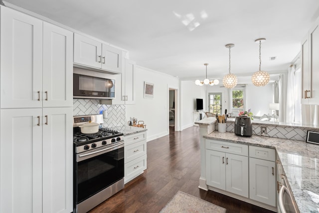 kitchen featuring tasteful backsplash, open floor plan, an inviting chandelier, stainless steel appliances, and a peninsula